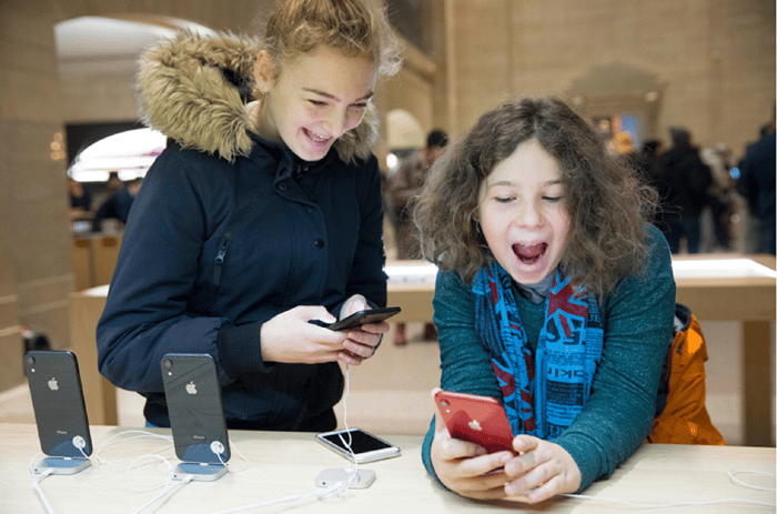 Two children jovially playing with display iPhones in an Apple Store.
