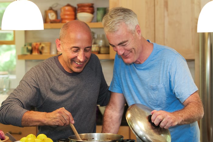 Two people cooking together and smiling.