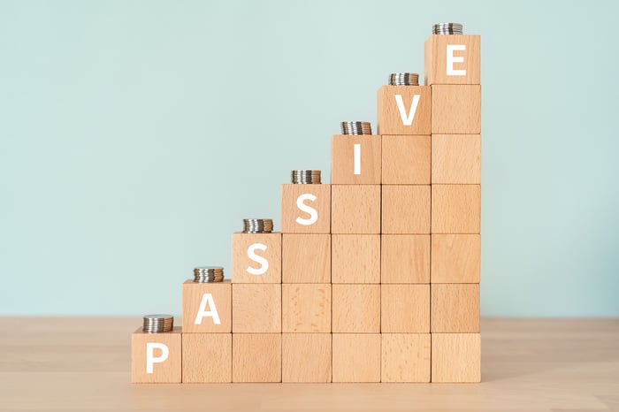 Increasingly large stacks of building blocks that spell out the word Passive, with stacks of coins on top of each group of blocks.
