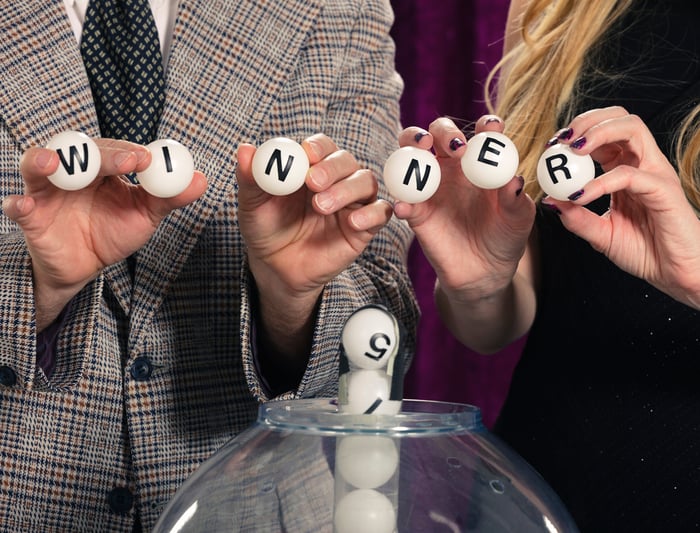 Two people holding up lottery balls that spell out winner.