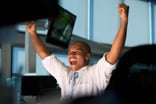 Person looking at computer monitor cheering because the stock market went up