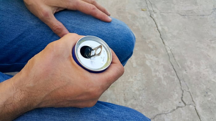 Person holding an open drink can.
