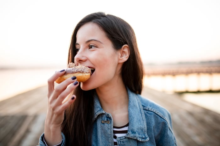Woman taking a bite of a pastry. 