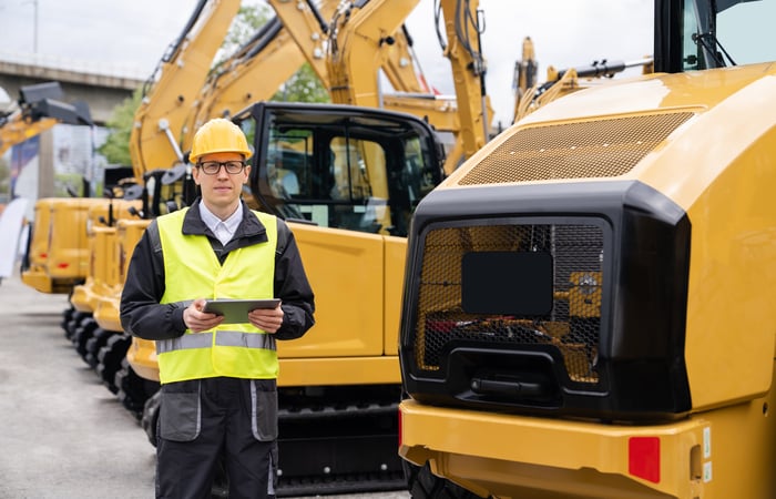 Person standing in front of construction vehicles.