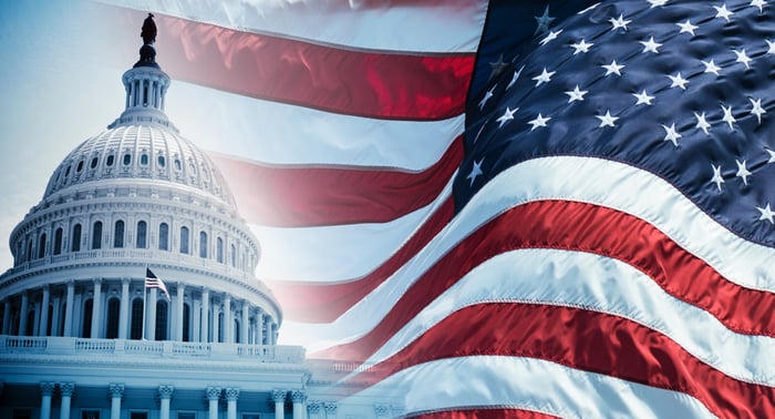 The U.S. Capitol building is shown in the foreground, with the background a reversed U.S. flag.