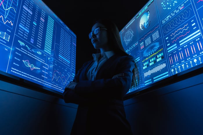 A person is standing between two digital displays.