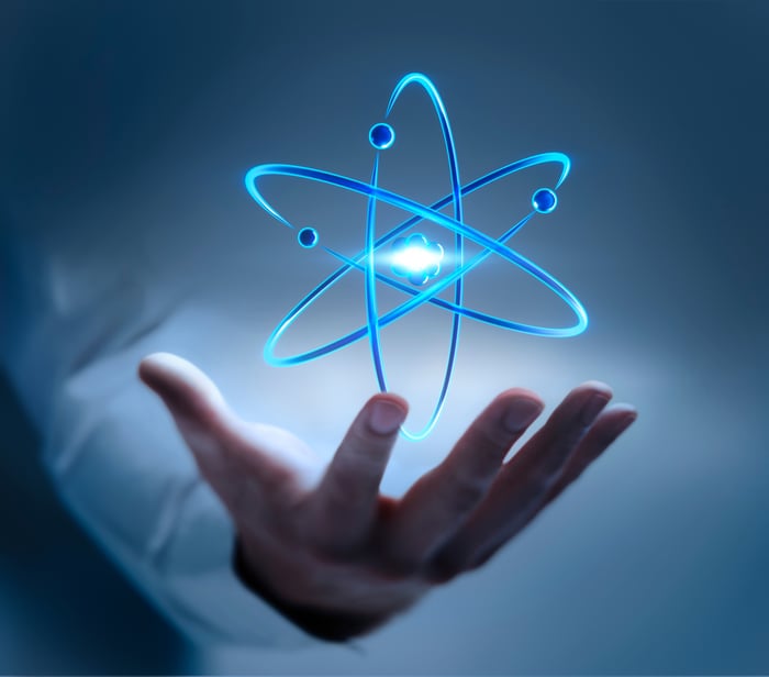 A blue model of an atom floats above someone's open hand