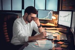 Downbeat office worker with many computer screens