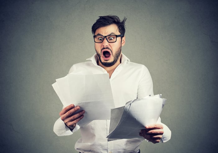 A person with a surprised look examines a document.