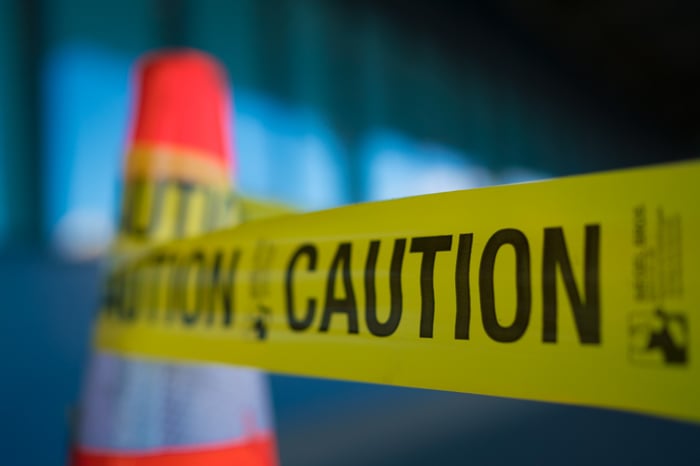 Caution tape on an orange cone.