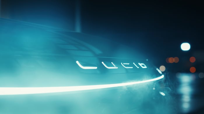 Front end of a Lucid EV with light bar and the word Lucid lit up in blue light.