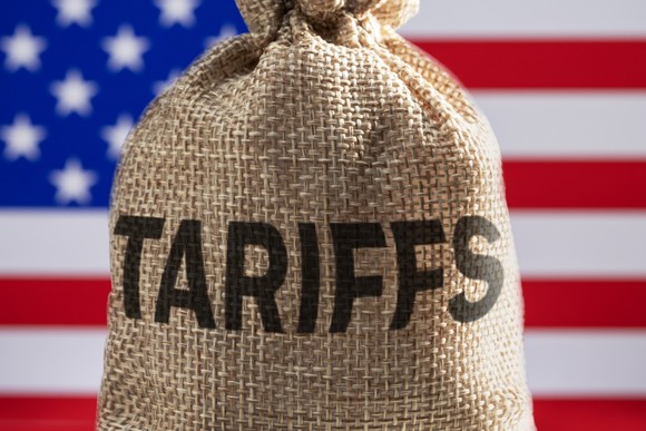 A burlap bag labeled tariffs in front of a U.S. flag.