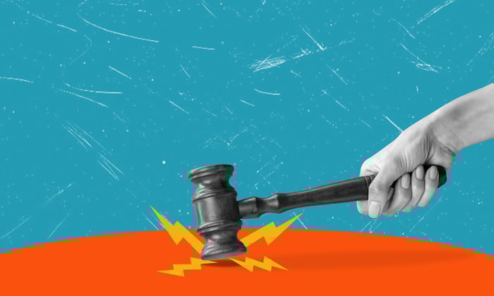 A gavel hitting an orange table with lightning coming out of its sides. 