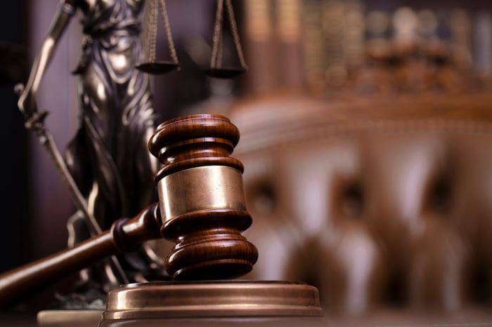 A gavel in a courtroom with Lady Justice in the background.
