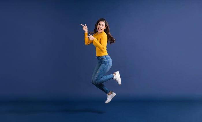 Woman in jeans jumps and points finger. 