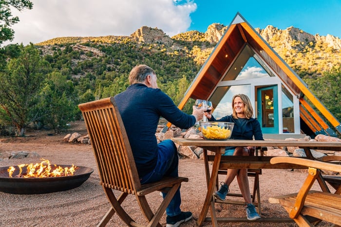 Couple dining outdoors in front of an A-frame vacation home.