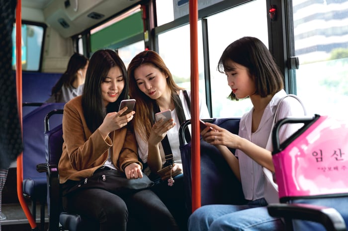 Friends on a bus sharing their smartphone finds.