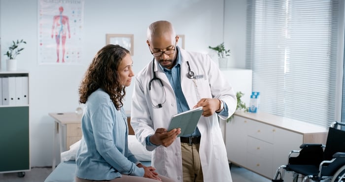 A doctor and patient talking in an examining room.