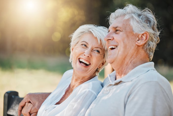 Laughing couple sitting outside holding hands.