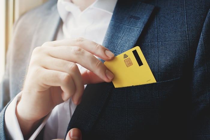 A person pulling credit card from front jacket pocket.