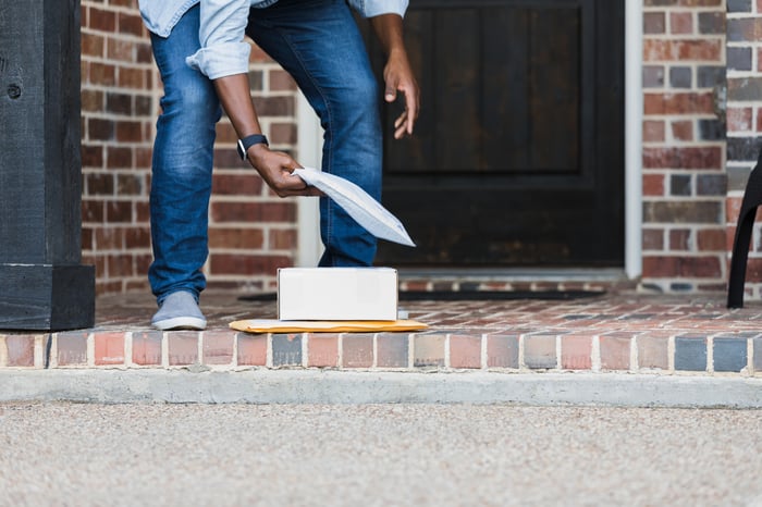 Person picking up packages on a front porch. 