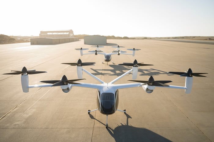 A row of Joby eVTOLs lined up on a runway in daylight.