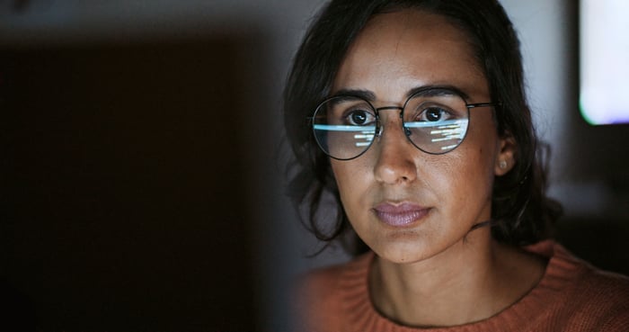 Someone is looking at a screen that's reflected in her glasses.