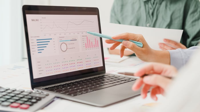 Investors study financial charts on a laptop.