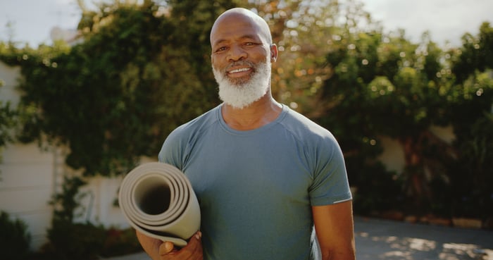 Someone outdoors, holding a yoga mat.
