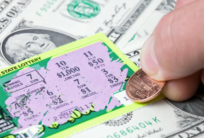 A person uses a penny to scratch off a lottery ticket.