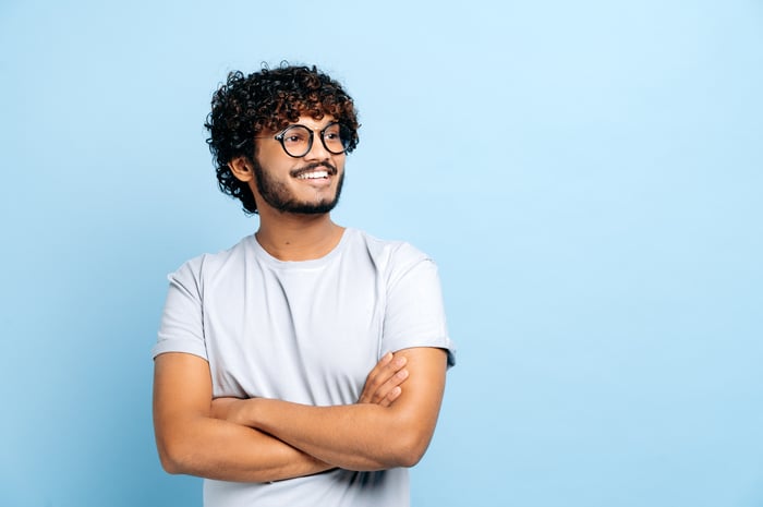 Person in a t-shirt with arms crossed smiling and looking away.