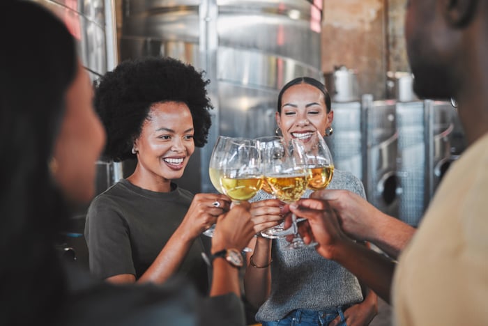 Four millennials enjoying themselves while toasting with partially filled glasses. 