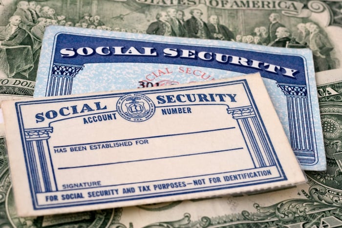 Two Social Security cards, lying on top of cash. 
