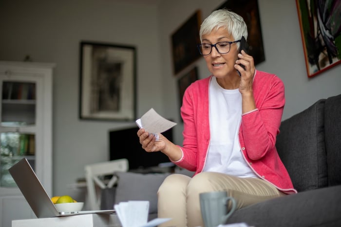 Person talking on phone and holding paper check.