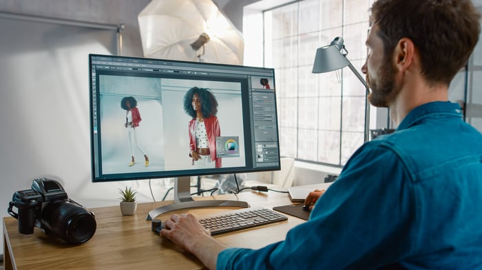 A person looks at a monitor while using creative software on an office computer.