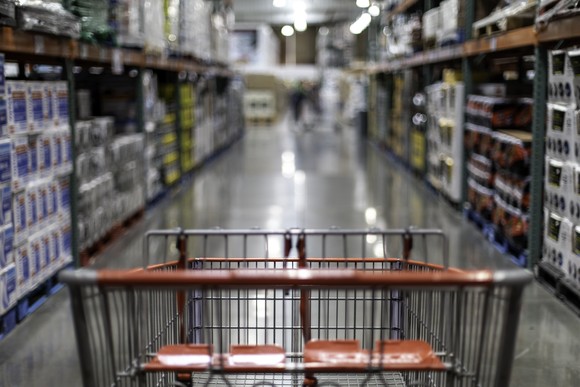 A shopping cart in the aisle of a wholesale retail store.