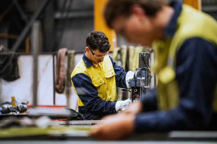Two workers at their stations on an industrial manufacturing line.