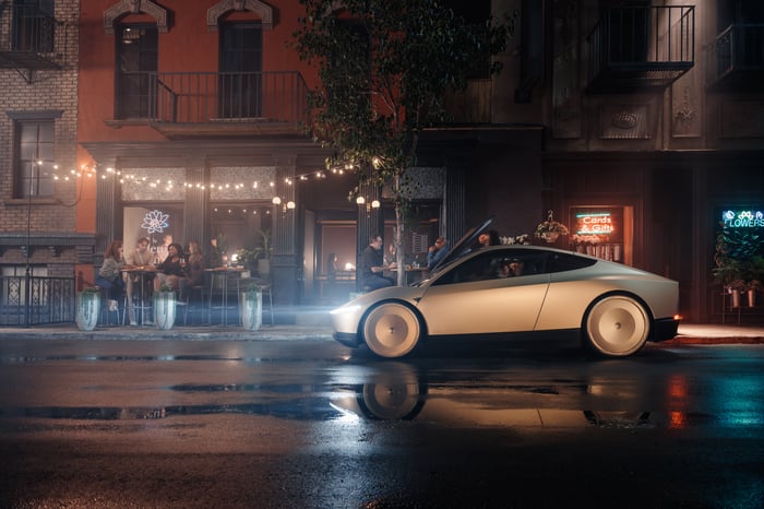 A Tesla Cybercab driving down a city street.