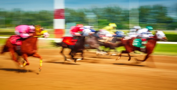 Blurred photo of racing horses in a horse race.