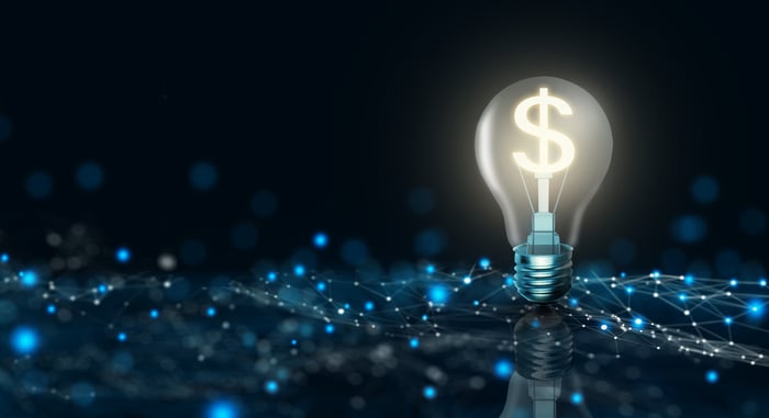 A dollar sign inside of a lightbulb that sits on top of bright dots connected by lines, illustrating the concept of passive income from stocks.