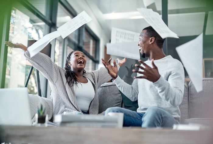 Happy young couple throw paper in the air in cafe lounge. 