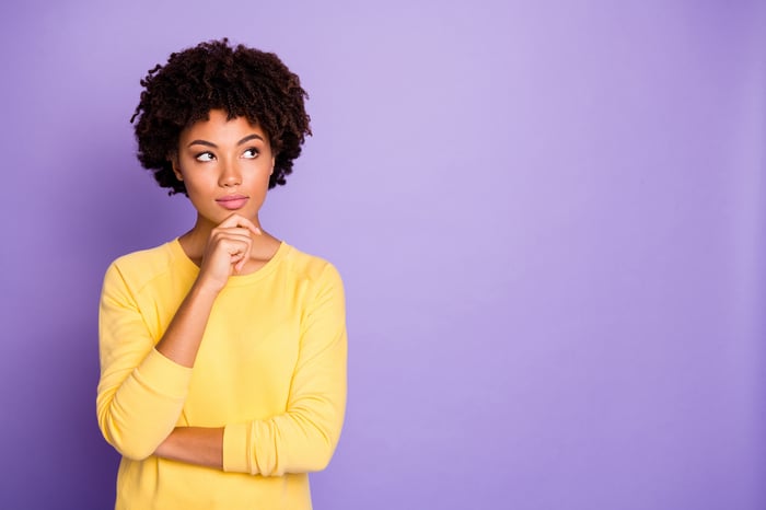 Someone in yellow is thinking, looking away with hand on chin.