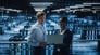 two engineers looking at a computer in a data center