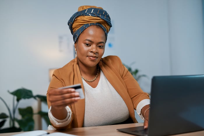 A person holds a credit card while using a laptop.