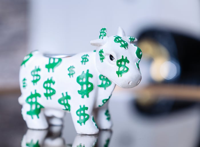 A white bull figurine with green dollar signs all over it.