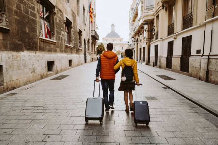 Two travelers walking while pulling suitcases. 