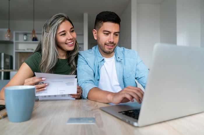 Two people look at a computer at home.