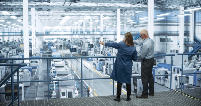 Two people standing and surveying a factory.
