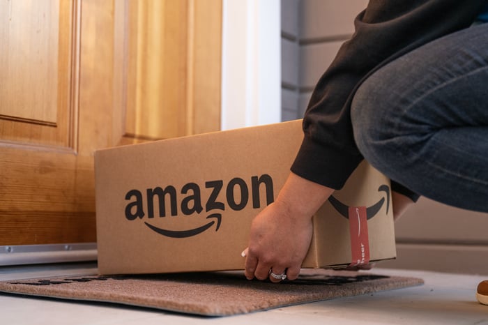 A delivery driver leaving an Amazon-branded package at a customer's door.