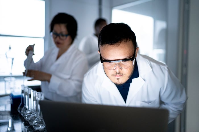 A researcher looks at something on a computer screen in a darkened lab.